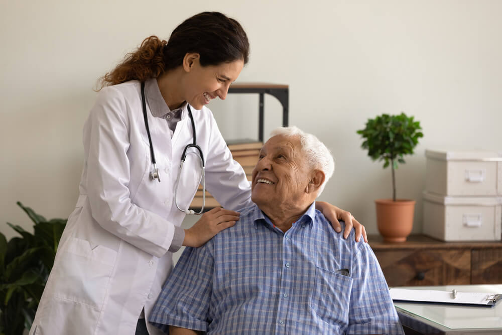 Doctora hispana con paciente mayor de edad sonriendo por tener seguro médico de Covered California