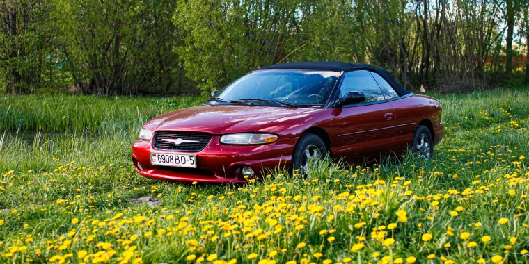 Chrysler Sebring rojo estacionado en un campo de flores – Seguro de auto barato para el Chrysler Sebring