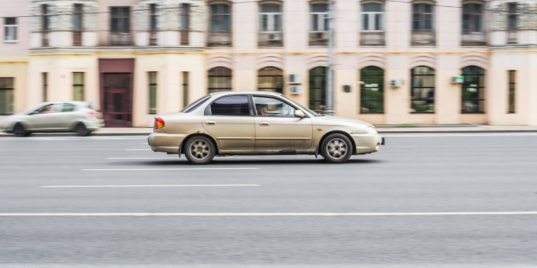 Kia Spectra dorado avanzando entre las calles – Seguro de auto barato para el Kia Spectra. 